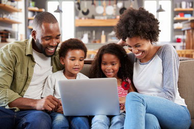 Smiling family using laptop at home, exploring conventional loan options for NY and PA homebuyers
